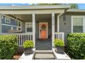 Inviting front porch featuring an orange door and beautiful landscaping at 6016 N Dexter Ave, Tampa, FL 33604