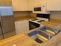 Bright kitchen with a stainless steel refrigerator, stove, microwave, and double basin sink at 642 Bird Bay E Dr # 205, Venice, FL 34285