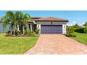 Beautiful home showcasing a brick driveway, tile roof, and tropical landscaping at 7683 Summerland Cv, Lakewood Ranch, FL 34202