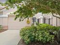 Charming townhome with a private garage adorned with a wreath and lush landscaping at 897 Lantern Way, Clearwater, FL 33765