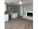 A modern living room with fireplace, white cabinets, an island, and hard wood floors at 1 Windrush Blvd # 84, Indian Rocks Beach, FL 33785
