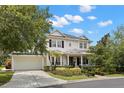 A two-story home with a manicured lawn, lush plants and bushes, and a driveway leading to an attached garage at 14617 Galt Lake Dr, Tampa, FL 33626