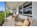 Relaxing front porch features wicker chairs, a small table, and view of the landscaped front yard at 1557 77Th N Ave, St Petersburg, FL 33702