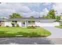 Charming single-story home featuring a manicured front lawn, landscaping, and a two-car garage at 1723 Cypress Ave, Belleair, FL 33756