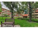 Building exterior featuring a bench, green lawn, and mature trees for a serene outdoor space at 3062 Eastland Blvd # 308, Clearwater, FL 33761