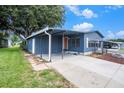 Charming blue home with a covered carport and cozy porch swing and fire pit at 3125 Beaver Creek Dr, Wesley Chapel, FL 33543