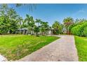 Beautiful exterior view of home featuring a well-manicured lawn, brick driveway and tropical plants at 3225 Rosery Ne Rd, Largo, FL 33771