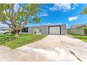 Front exterior view of home featuring a mature tree, grey paint, and a front-facing garage at 4016 Grayton Dr, New Port Richey, FL 34652