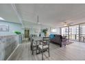 Inviting living and dining area with stylish furniture, a mirrored wall, and a ceiling fan; beach views through the windows at 440 S Gulfview Blvd # 701, Clearwater Beach, FL 33767