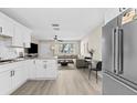 Bright and modern living area featuring an open floor plan into kitchen with white cabinets at 4718 W Oklahoma Ave, Tampa, FL 33616
