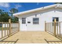 Bright white home with a new wood deck perfect for relaxing, complemented by a freshly painted front door at 9445 Cardy St, New Port Richey, FL 34654