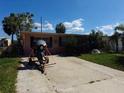 A single-story home with a brick facade, trailer, and motorcycle under a bright blue sunny sky at 13710 Frances Ave, Hudson, FL 34667