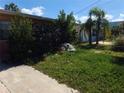 A partial view of the front yard with shrubs, sand bags, and palm trees at 13710 Frances Ave, Hudson, FL 34667