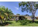 Charming single-story home with a manicured front lawn and a mature shade tree at 1868 Lombardy Dr, Clearwater, FL 33755