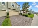 View of the townhome with a stone paver driveway and lush green landscaping at 19272 Blue Pond Dr, Lutz, FL 33558