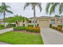 Charming one-story home with well-manicured landscaping, vibrant flowers, and towering palm trees at 2292 Sifield Greens Way # 59, Sun City Center, FL 33573