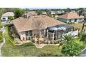 Tranquil backyard featuring a screened lanai, well-manicured lawn, and tropical landscaping at 2359 Emerald Lake Dr, Sun City Center, FL 33573