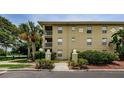 Well-manicured exterior of condo building with lush landscaping and nearby lake at 2690 Coral Landings Blvd # 122, Palm Harbor, FL 34684
