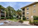 Exterior shot of condo building nestled among mature trees and verdant landscaping with pond views at 2690 Coral Landings Blvd # 122, Palm Harbor, FL 34684