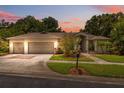 Charming single-story home with a well-manicured lawn, mature trees, and a two-car garage during sunset at 3037 Crest Dr, Clearwater, FL 33759