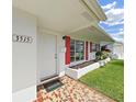 Close-up of the front entrance featuring mosaic tiles, red shutters, and a white door at 3515 100Th N Ter, Pinellas Park, FL 33782