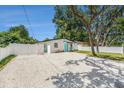 A well-maintained white home with a teal door, surrounded by white gravel and a white fence at 3617 E Louisiana Ave, Tampa, FL 33610