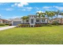 Charming home featuring mature landscaping, a gray roof, a well-manicured lawn, and a gray two-car garage at 425 4Th N Ave, Tierra Verde, FL 33715