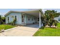 Light blue home with white trim, well-manicured lawn, and a covered carport at 427 Pelican S Dr, Oldsmar, FL 34677