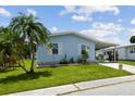 Charming light blue home with white trim, well-manicured lawn, and a covered carport at 427 Pelican S Dr, Oldsmar, FL 34677