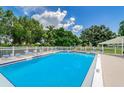 Community pool is surrounded by a white fence and lounge chairs under a partly cloudy, bright blue sky at 4580 Overlook Ne Dr # 191, St Petersburg, FL 33703