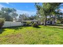 Well-maintained lawn, mature trees provide shade for a home with a clean white exterior and black trim at 489 W Davis Blvd, Tampa, FL 33606