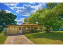 Charming single-story home featuring a well-manicured lawn and mature trees providing ample shade at 4906 N Arrawana Ave, Tampa, FL 33614