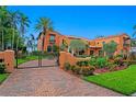 Orangey Spanish style home with brick driveway, manicured lawn, black metal gates and landscaping at 501 Brightwaters Ne Blvd, St Petersburg, FL 33704