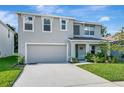 View of the two-story home with a manicured lawn, neutral stucco, attached garage, and an inviting covered entryway at 7737 Rosewood Garden Loop, Tampa, FL 33637
