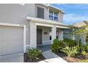 View of the front porch with supporting columns, muted gray door, desert-friendly landscaping, and a two-car garage at 7737 Rosewood Garden Loop, Tampa, FL 33637
