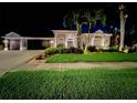 Stunning exterior showcasing manicured lawn, lush landscaping, and a well-lit home at night at 10675 Park Place Dr, Largo, FL 33778