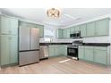 Modern kitchen with stainless steel appliances, green cabinets, and granite countertops at 12106 Clearbrook Ct, Riverview, FL 33569