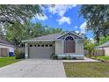 Charming single-story home featuring an attached garage and landscaped front yard with mature trees at 1319 Dew Bloom Rd, Valrico, FL 33594