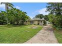 Inviting single-story home featuring lush greenery and a long driveway leading to a detached garage at 1533 Suffolk N St, St Petersburg, FL 33710