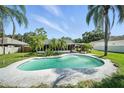 Beautiful backyard with a private pool, lush landscaping, and a covered patio area at 22422 Stillwood Dr, Land O Lakes, FL 34639