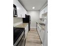 Galley kitchen boasts granite countertops, stainless appliances, white cabinets, and wood look tile at 3325 Bayshore Blvd # C14, Tampa, FL 33629