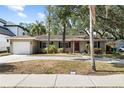 Charming single-story home with a well-manicured lawn, mature trees, and an attached garage at 3907 W Azeele St, Tampa, FL 33609