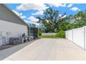 Paved backyard area featuring the house's air conditioning system, with the backyard and white fence behind it at 10811 Providence Oaks Dr, Riverview, FL 33578