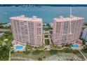 Aerial view showcasing pink condo buildings with beach access and a community pool at 1340 Gulf Blvd # 8C, Clearwater Beach, FL 33767