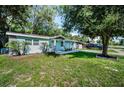 Well-maintained home featuring lush lawn, mature trees, and attractive stone architectural detail at 2121 Dodge St, Clearwater, FL 33760