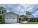 Single-story home with a two-car garage and beautiful landscaping including palm trees at 2210 Bayou Dr, Holiday, FL 34691
