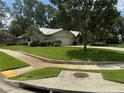 Inviting exterior of the home with a well-maintained lawn and mature trees in a desirable neighborhood at 2215 Toniwood Ln, Palm Harbor, FL 34685