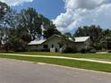 Charming home featuring a well-manicured lawn, mature trees, and an attached two-car garage at 2215 Toniwood Ln, Palm Harbor, FL 34685