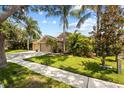 Inviting single-Gathering home with lush landscaping, mature palms, and a well-maintained lawn on a sunny day at 2511 Groveway Dr, Valrico, FL 33596