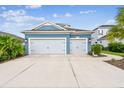 Beautifully landscaped blue home featuring a two-car garage and well-manicured lawn at 3326 Woodmont Dr, Parrish, FL 34219